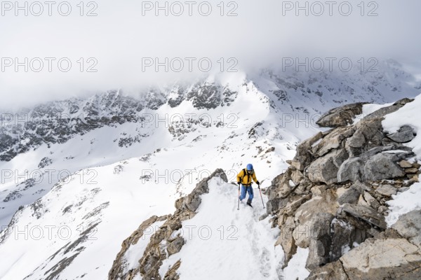 Mountaineers climbing the ridge of Piz Laviner, view of wintry mountain landscape, Grisons Haute
