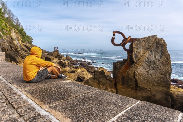 A young man in a yellow sweatshirt visiting the Peine del Viento in San Sebastián. Province of