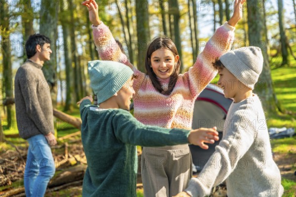Brothers and sister raising hands after stacking while enjoying a camping day with family in a