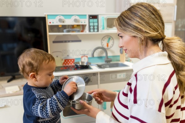 Mother and son enjoying playful moments together with a toy kitchen set in their cozy living room,