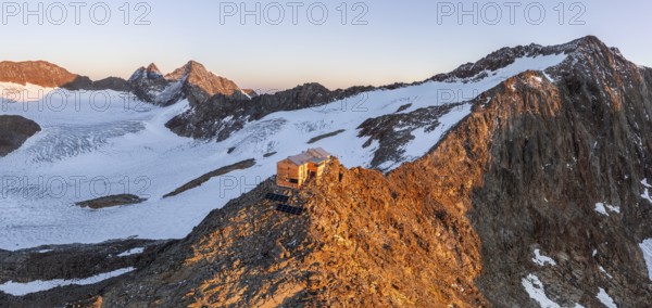 Atmospheric sunrise in a picturesque mountain landscape, alpenglow, aerial view, mountain hut