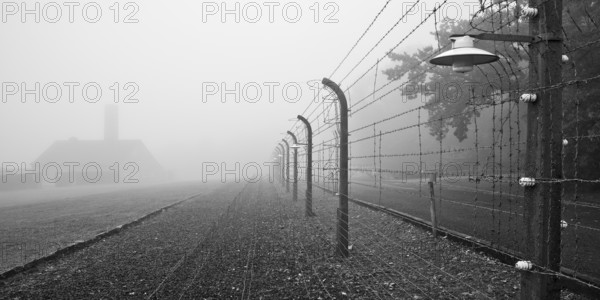 Reconstructed camp fence with crematorium in the fog at beech forest concentration camp, now a