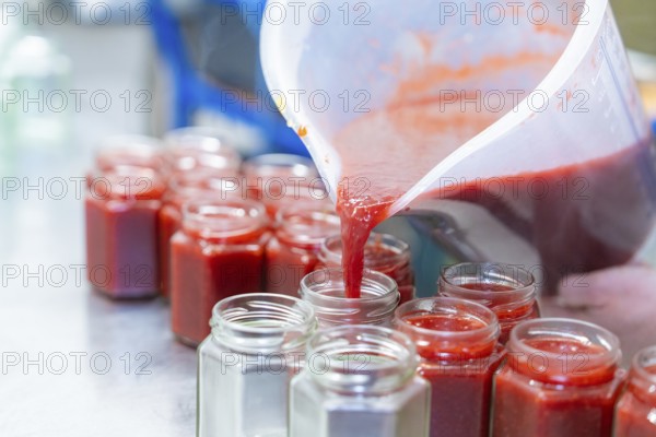 Strawberry mixture is filled into jars from a large measuring cup, jam production, Haselstaller
