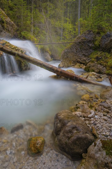 A tree trunk lies across a waterfall, long exposure, Dolomites, Puez-Geisler nature park Park, St.