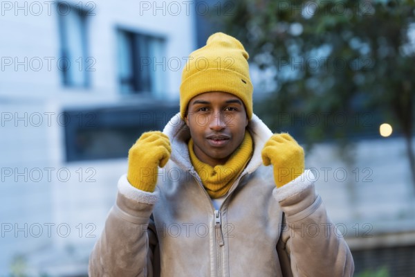 Stylish man wearing a bright yellow hat, gloves, and scarf, braving the cold winter weather while