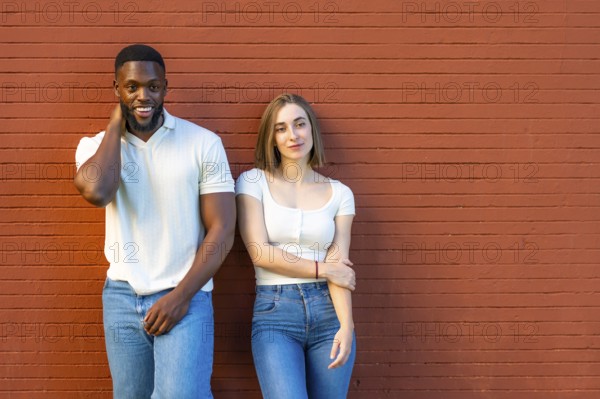 Horizontal photo with copy space of a shy multi-ethnic couple in denim clothes leaning on urban