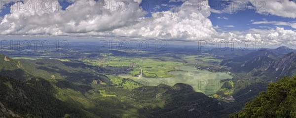 Panoramic view from Herzogstand down to a mountain landscape with Lake Kochel and cloudy sky,