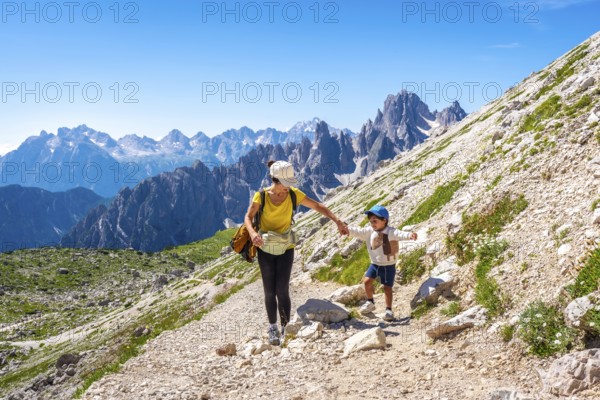 Tourists enjoying a summer hike on a mountain trail in the italian dolomites, with the tre cime di