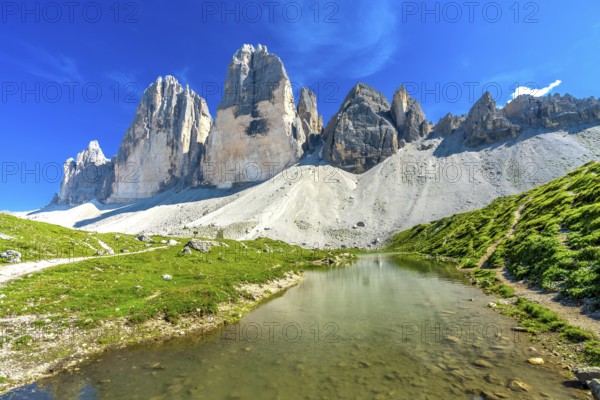Scenic view of tre cime di lavaredo and its reflection in a mountain lake during a sunny summer day