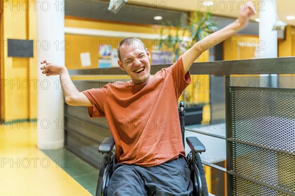 Successful man with disability celebrating in a modern coworking sitting on wheelchair and raising
