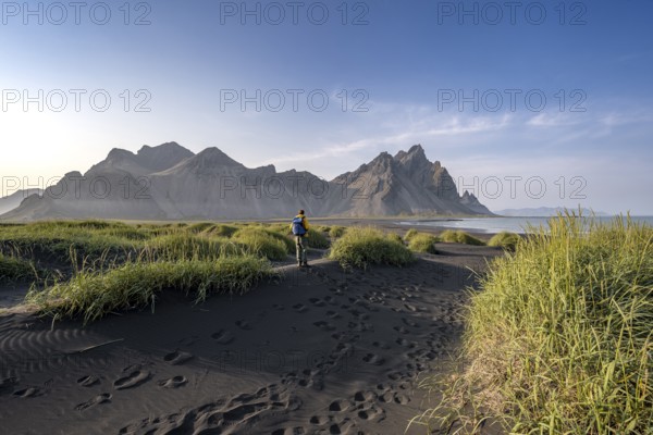 Tourist on a sand dune, Black beach with volcanic sand, Sand beach, Dunes with grass, Stokksnes