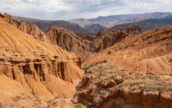 Eroded mountain landscape with sandstone cliffs, canyon with red and orange rock formations,