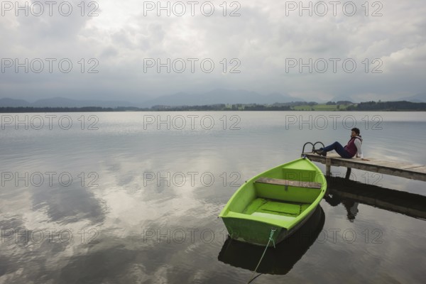 Woman 50-55, wooden jetty, green rowing boat, Hopfensee, Hopfen am See, near Füssen, Ostallgäu,