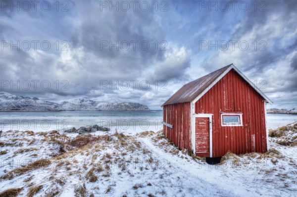 High Dynamic Range (HDR) image of red rorbu house shed on beach of fjord. Skagsanden beach, Lofoten