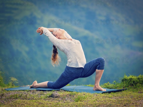 Yoga outdoors, sporty fit woman practices Hatha yoga asana Anjaneyasana, low crescent lunge pose