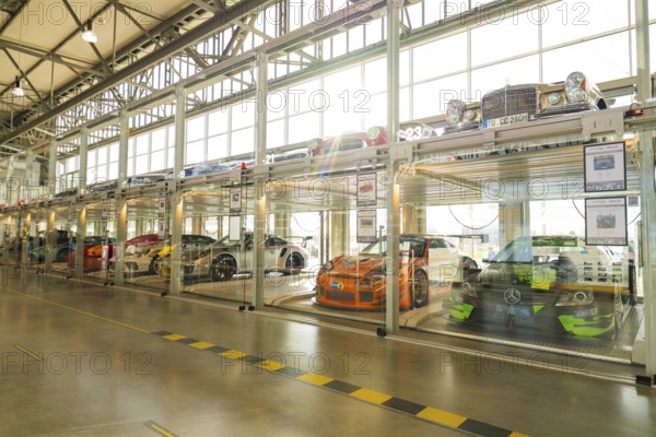Cars in a two-storey glass garage with natural daylight and minimalist design, Motorworld