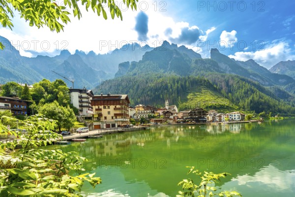 Stunning summer view of alleghe village reflecting on the emerald waters of lake alleghe,