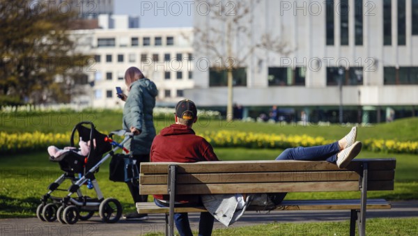 A couple relaxing on a park bench in the city garden in times of the corona crisis, Essen, Ruhr