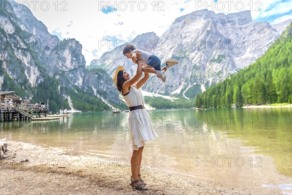 Tourist mother lifting her son in the air while enjoying summer holidays at lake braies, also