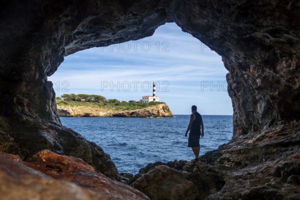Tourist stands inside the arc natural cave in portocolom, mallorca, admiring the scenic view of a