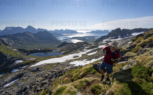 View of mountains and fjord landscape, mountaineers at the summit of Rundfjellet, Austenesfjord and