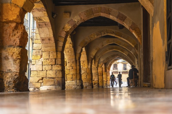 Tourists walking through the arches of the medieval city of tarragona, spain, enjoying the
