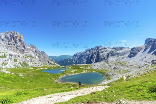 Breathtaking view of the tre cime di lavaredo and the surrounding lakes with a tourist enjoying the