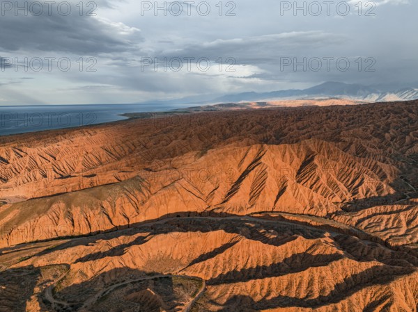 Landscape of eroded hills, badlands at sunset, Issyk Kul Lake in the background, aerial view,
