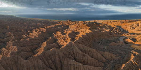 Riverbed runs through a landscape of eroded hills, badlands at sunset, Issyk Kul Lake in the
