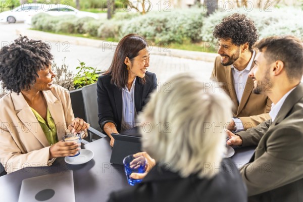 Multi-ethnic business people drinking coffee working with digital tablet sitting relaxed in a