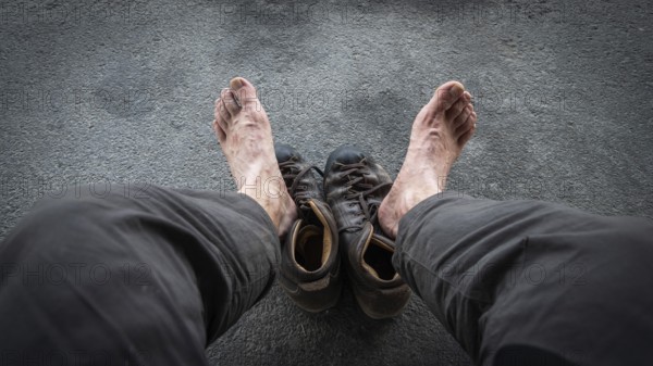 View of two bare feet of a pilgrim, worn hiking boots on dark ground, pilgrimage route Olavsweg or