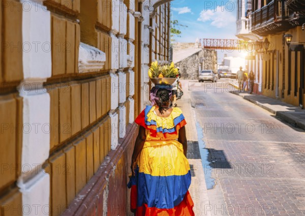 Colombia, lady in national colorful costume walking the streets of Walled City historic center of