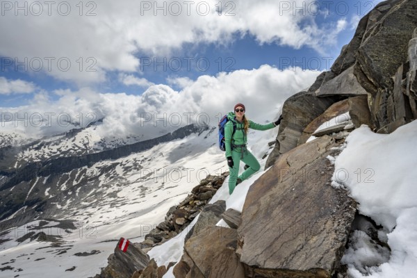 Mountaineer on a rocky hiking trail with snow, mountain panorama with snow-covered mountain peaks
