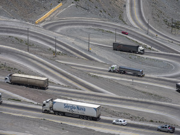 Heavy traffic of trucks on mountain pass Los Caracoles, The Snails, road connecting Chile and