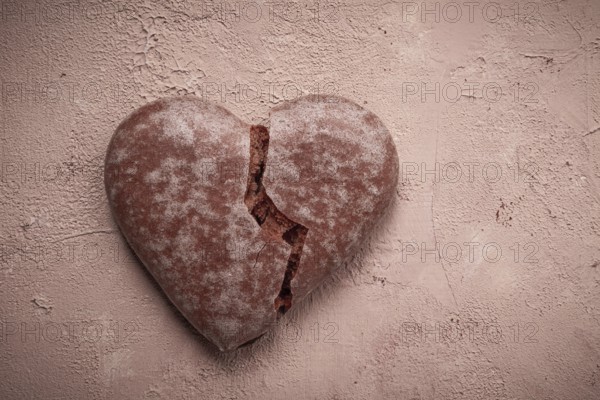Glazed chocolate gingerbread, heart-shaped, top view, a broken heart, close-up, on beige