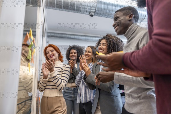 Side view of multi-ethnic group of colleagues applauding after a successful brainstorming process