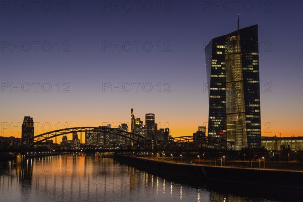 The lights in the offices of the European Central Bank (ECB) and the Frankfurt skyline glow in the