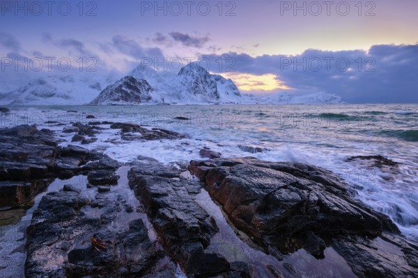 Beach of Norwegian sea on rocky coast in fjord on sunset in winter. Vareid beach, Lofoten islands,