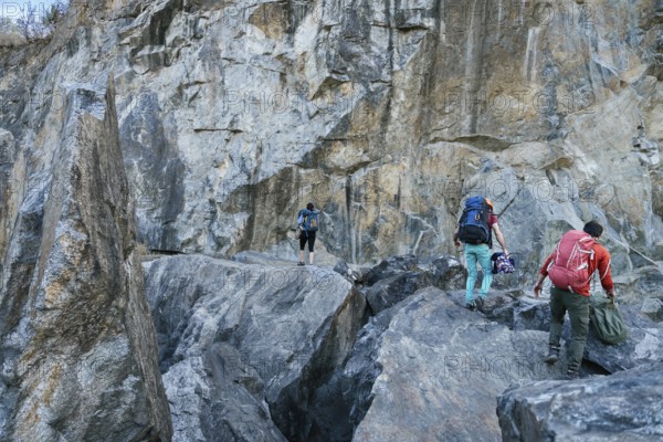 Climbers preparing for ascent. Three male female persons walking on the rocks. Extreme outdoor