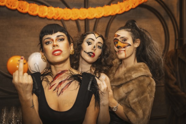 Female friends in costumes at halloween party with friends in disco nightclub, looking at camera