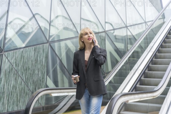 Entrepreneurial girl in business park in a modern building with escalator, young blonde in a suit