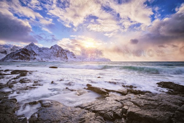 Beach of Norwegian sea on rocky coast in fjord on sunset in winter. Vareid beach, Lofoten islands,