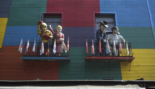Colourful house facades with balconies and figures, decorated with flags, La Boca district, Buenos
