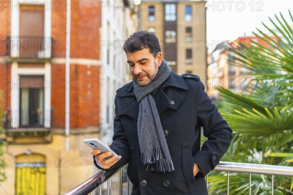 Three quarter length portrait of a caucasian adult casual businessman using phone standing in a