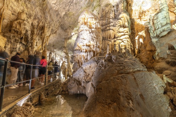 Tourists observing the magnificent stalactites and stalagmites formations inside postojna cave, a