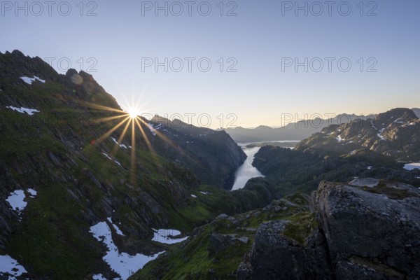 Picturesque mountain landscape at sunrise with sun star, fjord Trollfjord and Raftsund, hike to