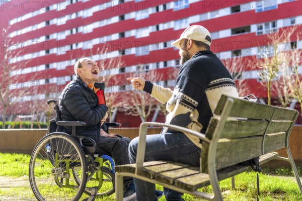 Two men enjoying time together in urban park, one using wheelchair, demonstrating inclusion and