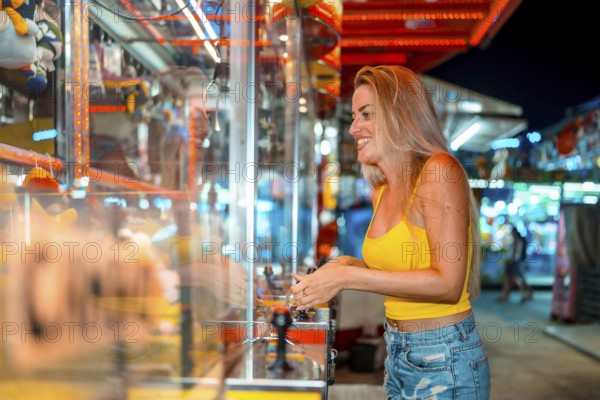 Excited blonde woman having fun playing arcade games at fair at night