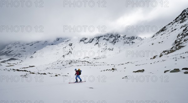 Ski tourers in a wintry mountain landscape with cloudy mountain peaks, ascent to Piz Laviner,