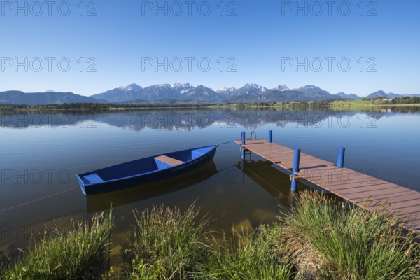 A blue jetty on a calm, clear lake with a breathtaking Alpine backdrop, Hopfen am See, near Füssen,